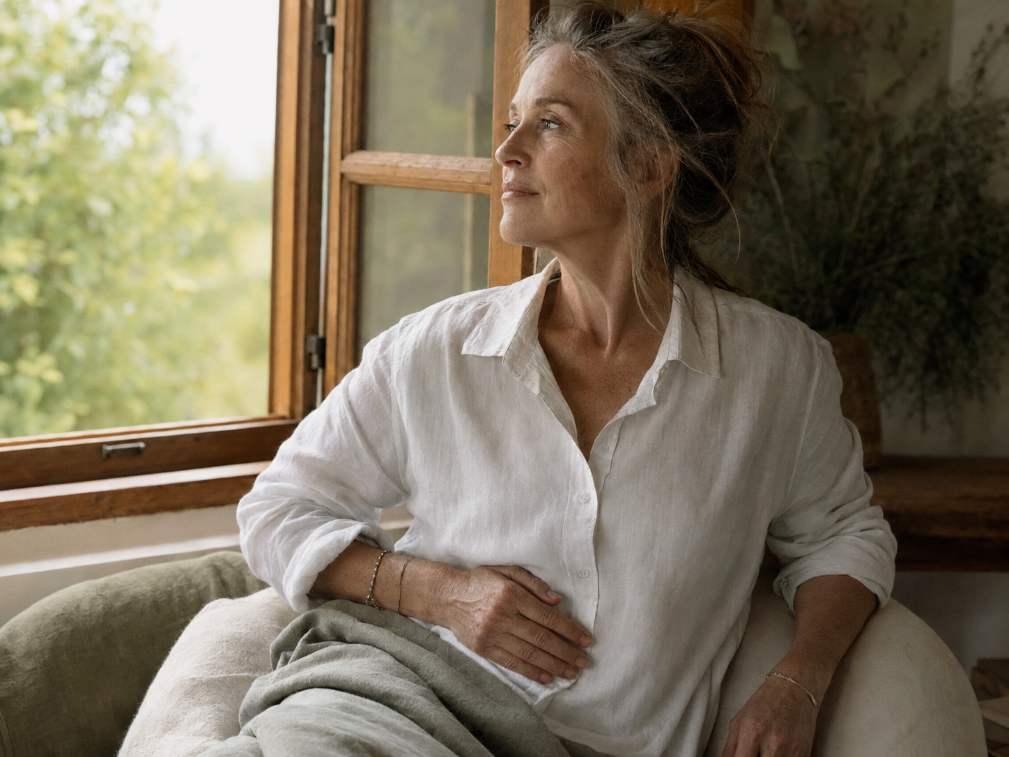 A woman sitting quietly beside an open window, noticing what is present